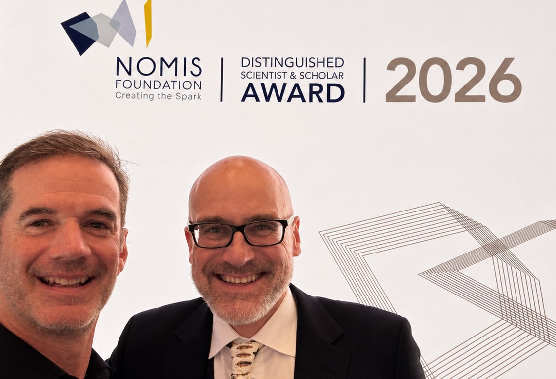 Owen Petchey (left) and Andrew Gonzalez (right) smiling in front of the NOMIS Foundation Distinguished Scientist & Scholar Award 2026 backdrop.